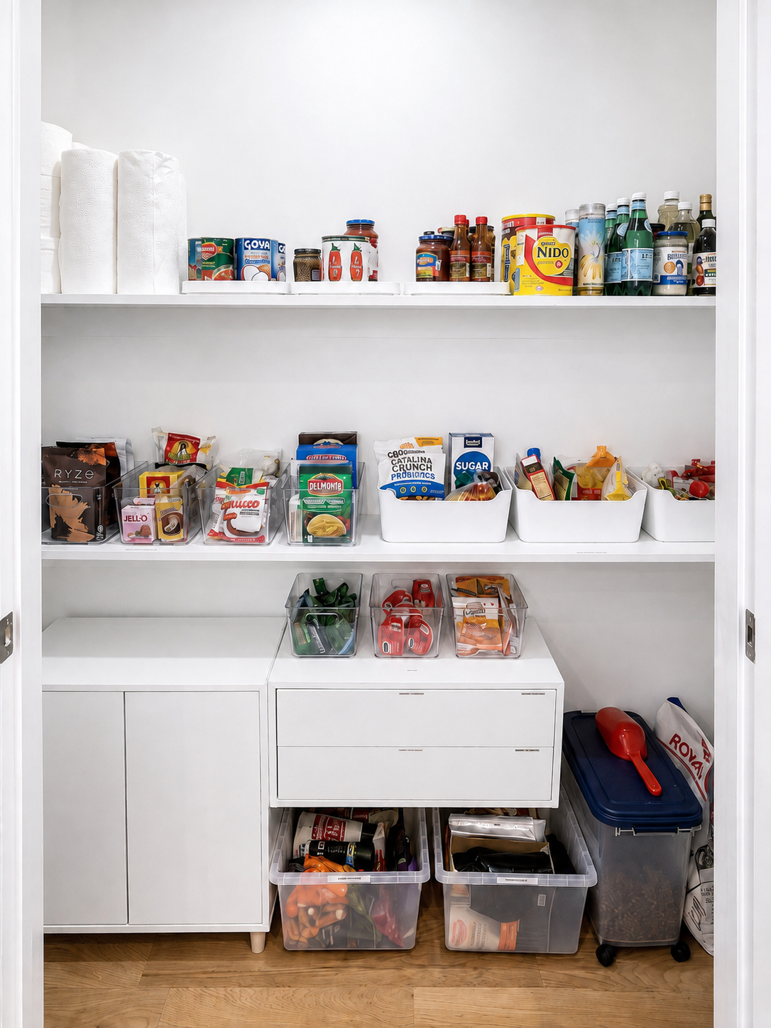 The same pantry after organizing, with labeled clear bins, baskets and grouped food categories