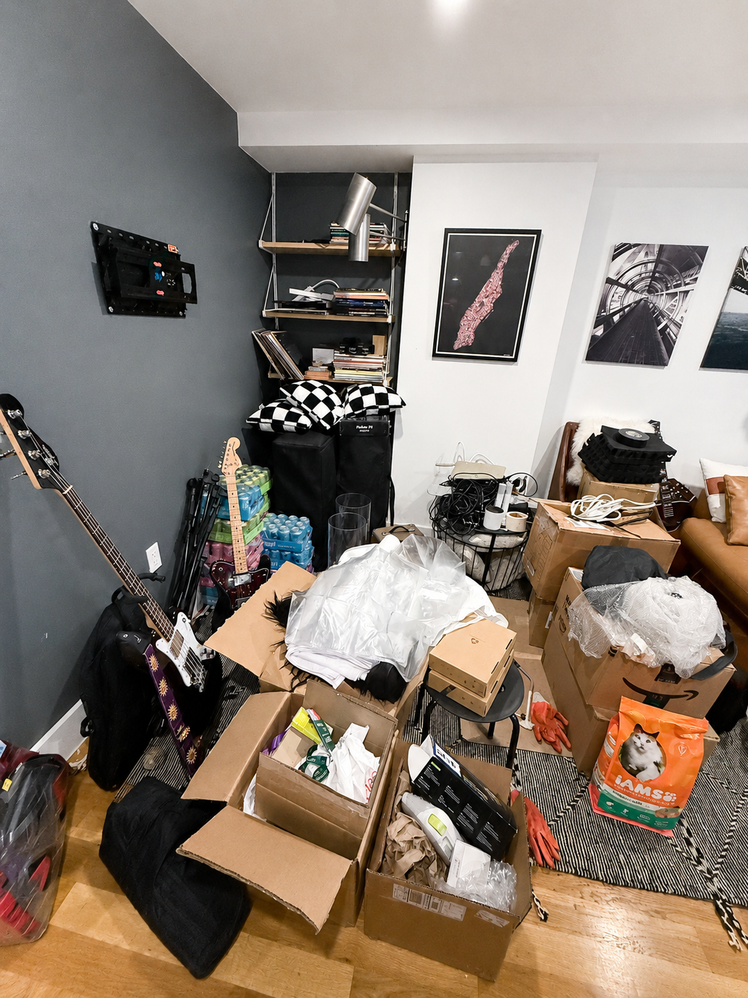 Music room during a move, filled with open cardboard boxes, guitars, cables and packing material