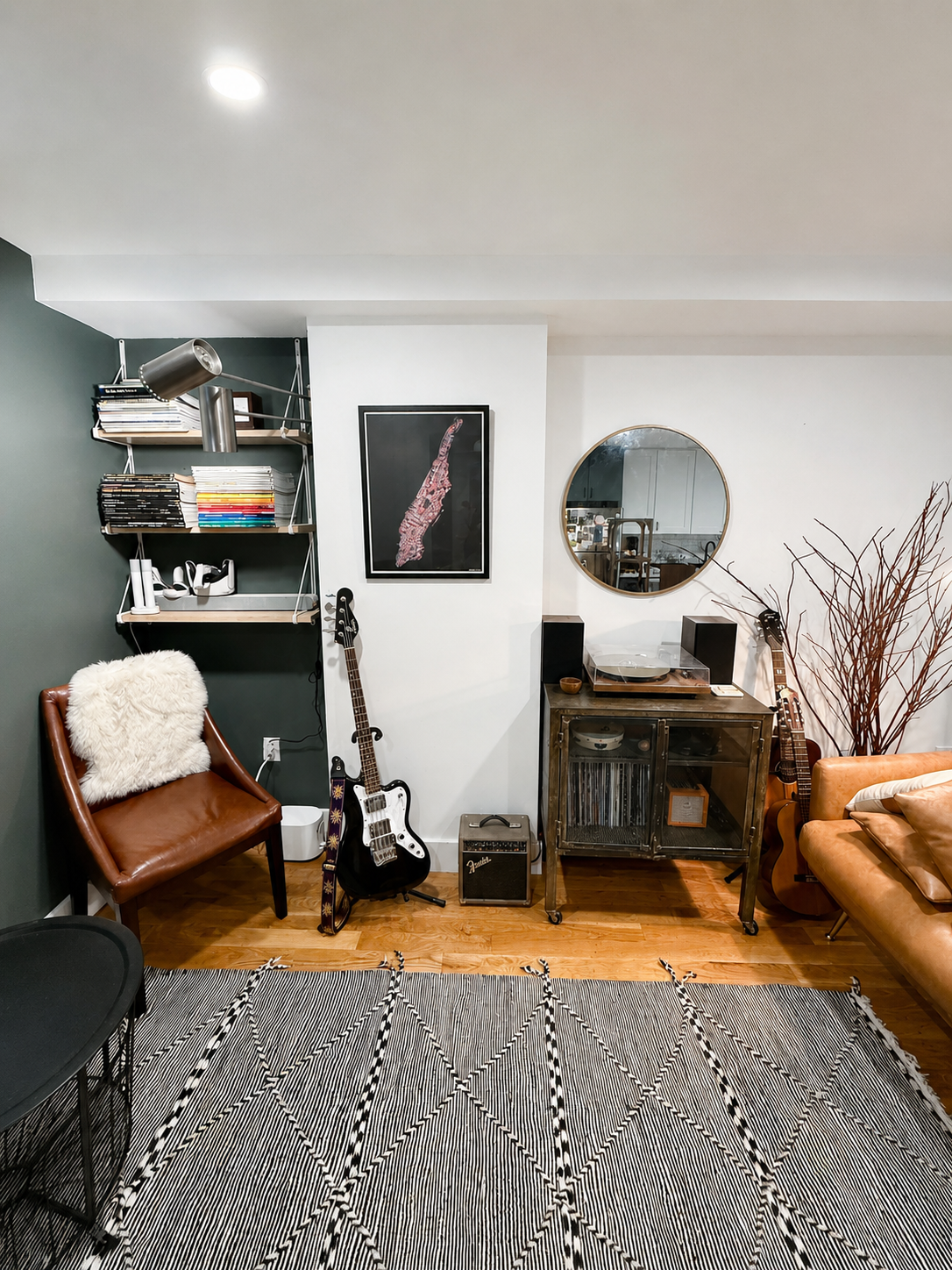 The same music room after organizing, with guitars displayed, records shelved on a metal cabinet and a styled reading corner
