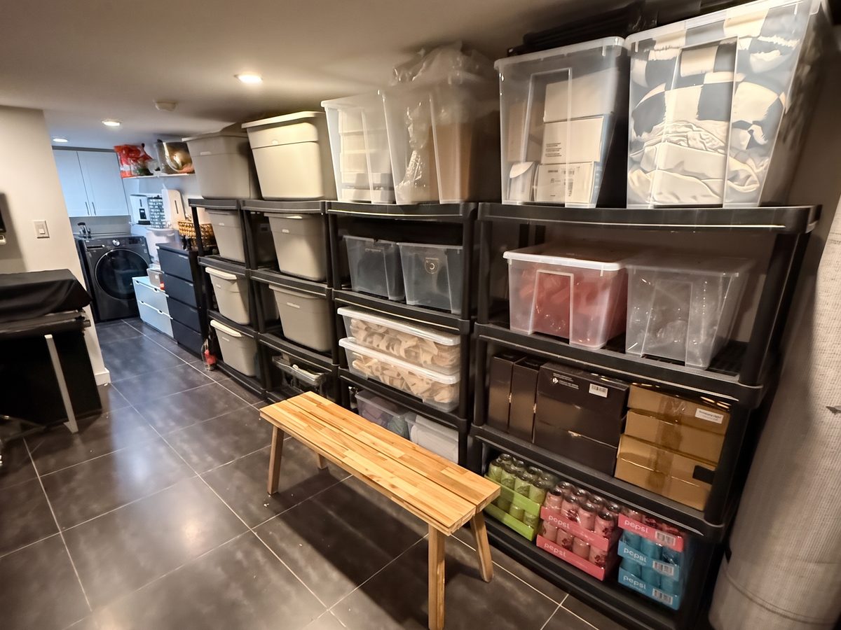 Basement after organizing, with labeled clear bins grouped by category on black shelving