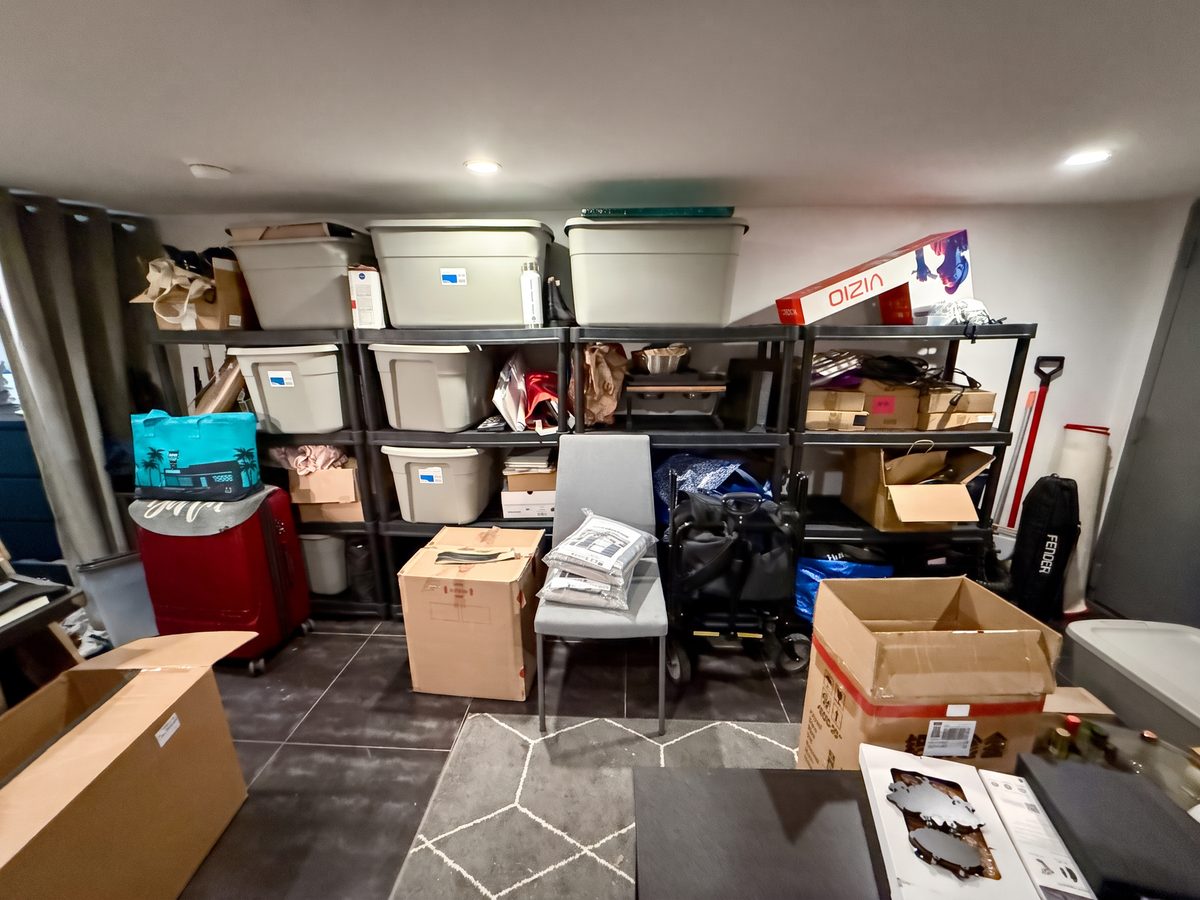 Basement before organizing, with storage bins, suitcases and open boxes filling the shelving and floor
